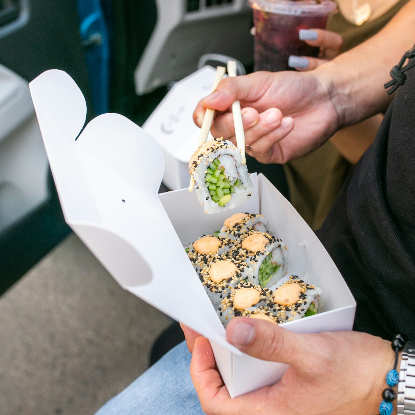 Customer eating sushi from takeaway packaging on the street